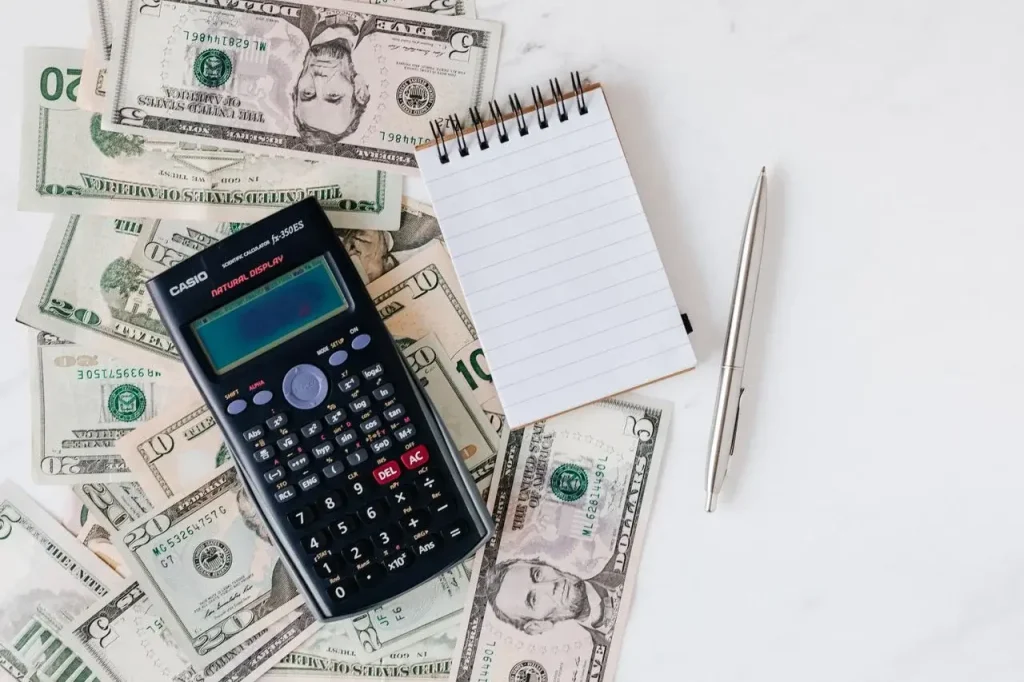Flat lay of US dollar bills with calculator and notebook for budgeting