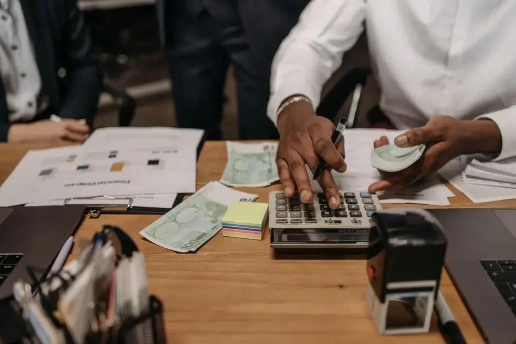 Professional setting with people handling cash and calculations using a calculator at a desk