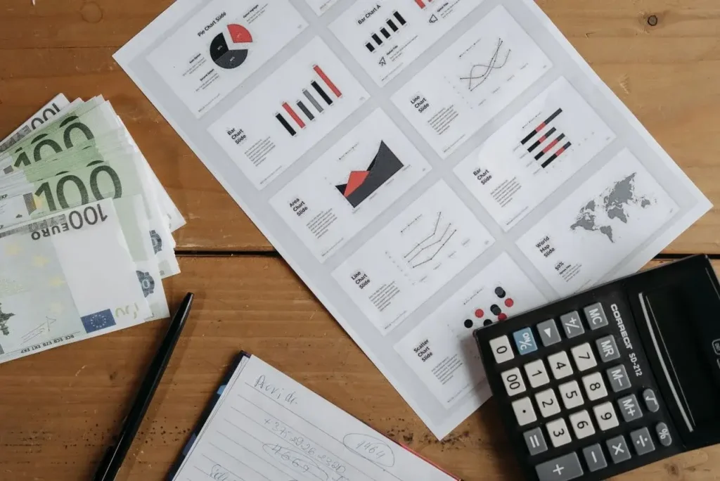 Euro banknotes, graphs, and calculator on a wooden table setup for financial analysis image