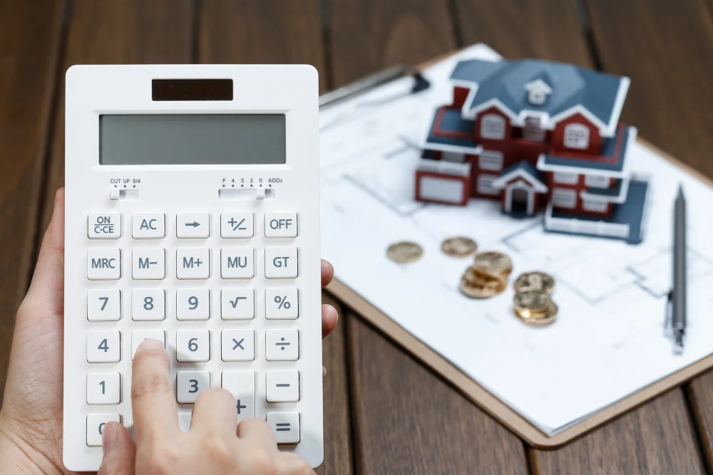 A-female-hand-operating-a-calculator-in-front-of-a-villa-house-model